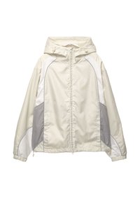 Ljusbeige vindjacka med huva och färgblock i vitt och grått, frontdragkedja, elastiska ärmslut och diskret logga på bröstet.