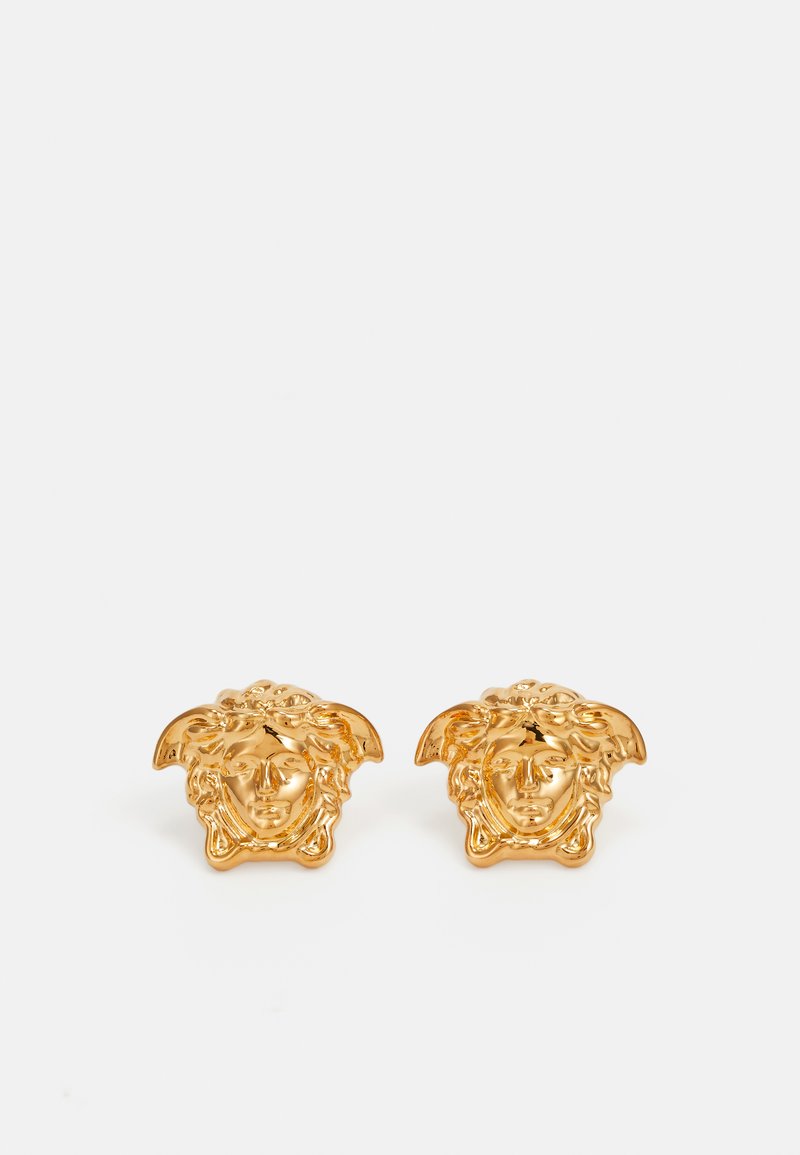 Boucles d'oreilles en or avec un design détaillé de visage et des cheveux stylisés. La forme est un petit carré arrondi avec un travail en relief complexe.