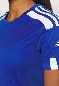 Blå atletisk skjorta med rund hals, korta ärmar och vita ränder på axlarna; tillverkad av mjukt, ventilerande tyg.