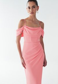 Dolga, oprijeta obleka iz mehke roza tkanine. Ima odkrite ramenske spuščene rokave, strukturirano korzetasto zgornjo polovico in subtilne naborke spredaj.