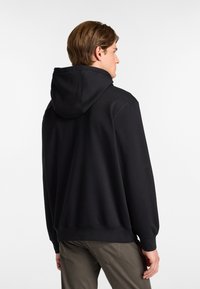 Sudadera negra con cordón, mangas largas y bolsillo canguro. Textura suave, corte relajado y puños y dobladillo acanalados.