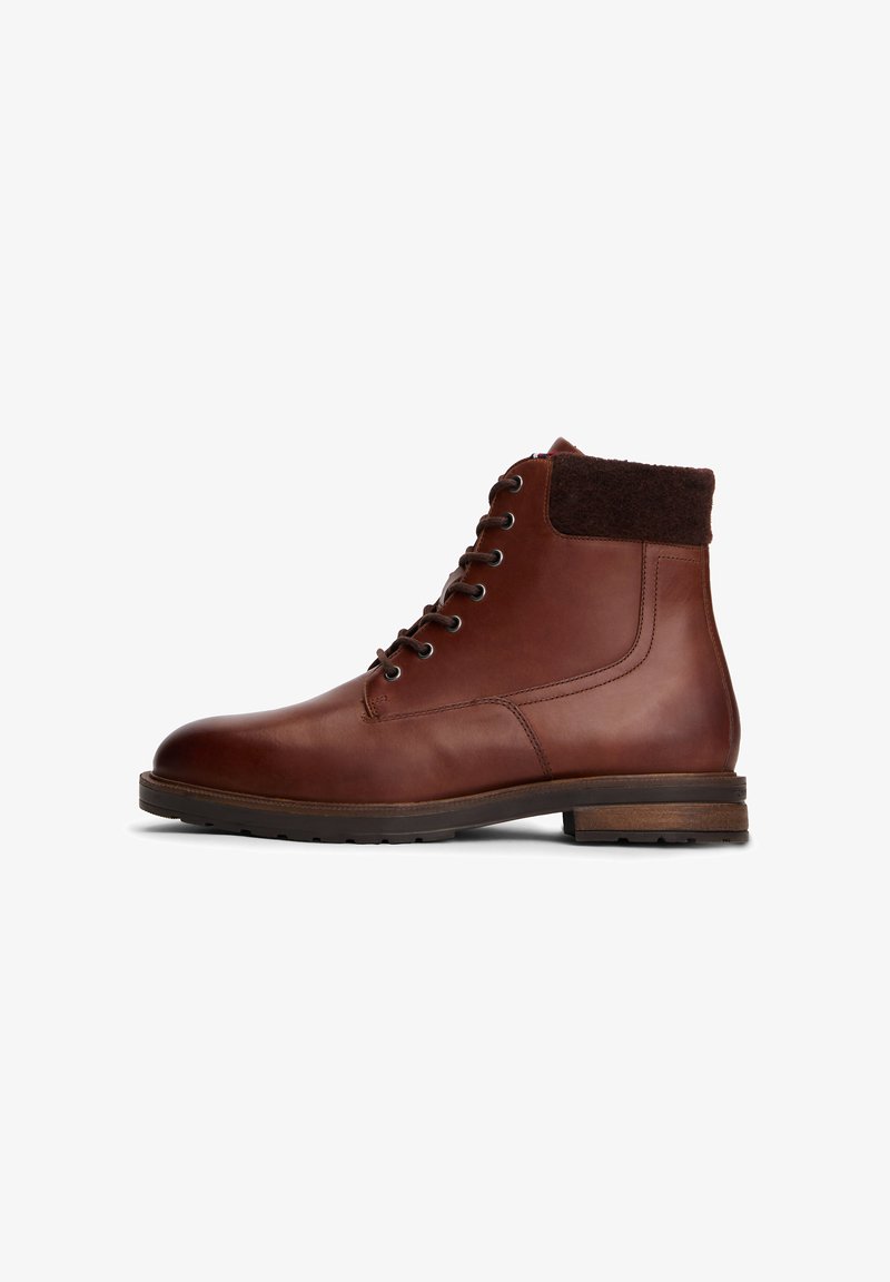 Brown leather ankle boot with a dark brown wool collar, rounded toe, and five metal eyelets for laces, featuring a textured rubber sole.