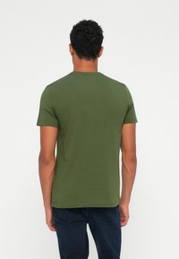 Olivengrøn kortærmet t-shirt lavet af bomuld, med rund hals og en glat overflade. Bagvisningen viser trøjets enkle design og pasform.
