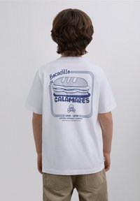 White cotton t-shirt featuring a navy graphic of a sandwich with text. Short sleeves and a relaxed fit. Designed for casual wear.