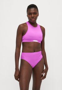 Conjunto de bikini atlético rosa, com um topo de corte alto e parte de baixo de cintura alta. Tecido suave e elástico com detalhe do logótipo na cintura.