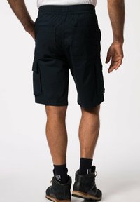 Shorts cargo en un oscuro tono marino con cintura elástica, múltiples bolsillos y un ajuste relajado, combinados con botas negras y calcetines marinos.