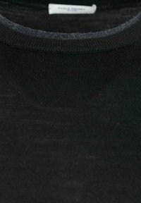 T-shirt in cotone nero con collo a giro, caratterizzato da un orlo ribattuto, una texture morbida e una vestibilità regolare. Etichetta visibile all'interno del colletto.