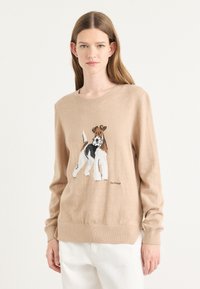 Pulover bej din material tricotat moale, având o ilustrație cu un câine. Manșete și tiv cu dungi, cu textul logo sub design.