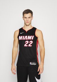 Crni košarkaški dres s natpisom "MIAMI" u bijeloj boji preko grudi, s brojem "22" u bijeloj boji, te crvenim i žutim bočnim detaljima.