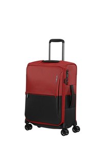Red fabric suitcase with black accents, telescopic handle, four wheels, zipped compartments, and a combination lock on the side.