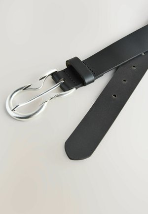 Cintura in pelle nera con una fibbia argentata a doppio dente. La cinghia presenta cuciture e diversi fori per la regolazione, con una texture liscia.