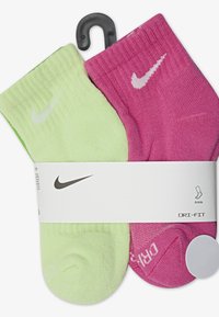 To sæt ankelstrømper: et limegrønt og et klart pink. Begge har en ribbet tekstur og et hvidt Nike-logo. Pakket med et hvidt bånd.