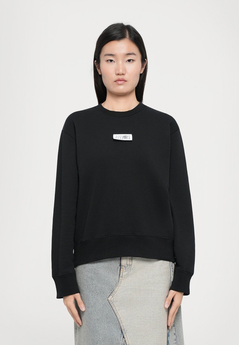 Black sweatshirt with a round neckline and long sleeves. Features a white rectangular logo on the chest. Soft fabric, relaxed fit.