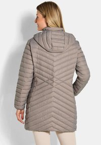 Lichtgewicht, gewatteerde jack met capuchon in zacht taupe met chevronsteek. Gladde textuur en middellange ontwerp.