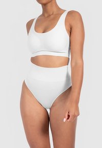 Witte bralette en hooggetailleerde bikini set gemaakt van glad, rekbaar materiaal, met een eenvoudig ontwerp en naadloze constructie.