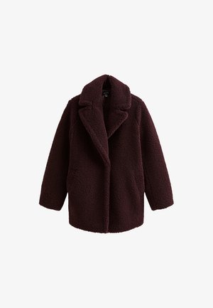 Manteau teddy long à manches longues de couleur bordeaux foncé, avec un large col à revers et un tissu en polaire doux et texturé, présenté sur un fond blanc.