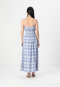Abito lungo con stampa floreale blu su fondo bianco, busto arricciato, spalline sottili e gonna fluida. Presenta una vestibilità lunga e rilassata.