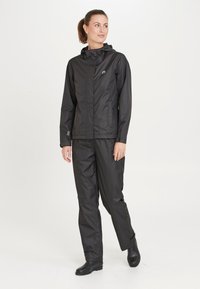 Sort vandtæt jakke med hætte og fuld lynlås, kombineret med matchende bukser. Fremstillet af glat, skinnende materiale; minimalistisk design, ingen synlige mønstre.