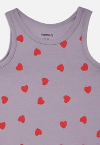 Svetlofialové tielko s opakujúcim sa vzorom červených sŕdc, vyrobené z mäkkej bavlnenej látky s okrúhlym výstrihom a bez rukávov.