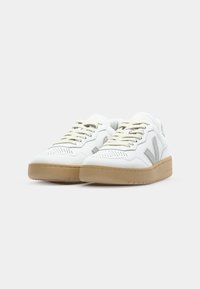 Witte sneakers met een gestructureerd leren bovenwerk, voorzien van grijze accenten, geperforeerde neus en een rubberen gumzool. Inclusief vetersluiting.