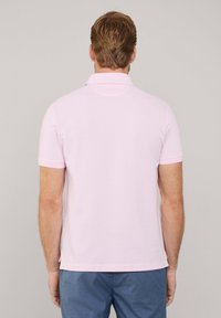 Lichtroze poloshirt met korte mouwen, uitgerust met een klassieke kraag en zijsplitten, gemaakt van een gladde, ademende stof.