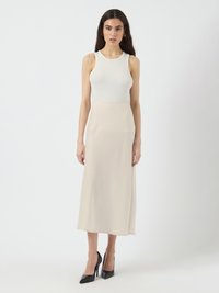 Top alb cu dungi, fără mâneci, asociat cu o fustă lungă, netedă, de culoare bej și pantofi cu vârf ascuțit, negri. Design simplu, fără modele vizibile.
