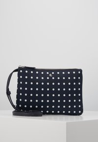 Marinblå kuvertväska med prickar, tillverkad av slitstark tyg med dragkedja och avtagbar rem; har vita prickar i ett enhetligt mönster.