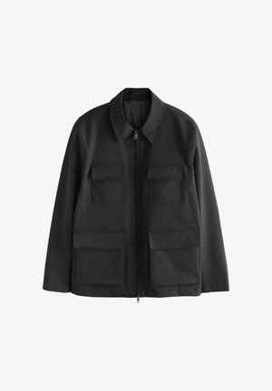 Musta vetoketjullinen takki, jossa on neljä suurta läppätaskua, pitkät hihat ja kärjellisellä kauluksella varustettu malli, esillä valkoisella taustalla.