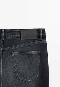 Svarta denimjeans med en läderetikett i midjan. Har en bakficka, blekt mönster och klassisk fem-fickdesign.
