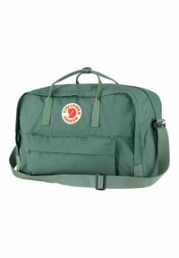 Borsa da viaggio in tessuto verde con due manici superiori e una tracolla removibile. Presenta una tasca frontale con zip e un patch rotondo con logo.