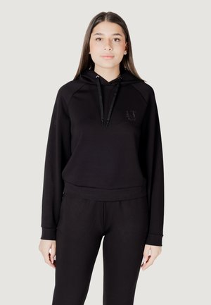 Felpa nera in misto cotone con tasca frontale, cappuccio con coulisse e polsini a costine. Presenta un logo discreto sul petto. Abbinata a pantaloni jogger coordinati.