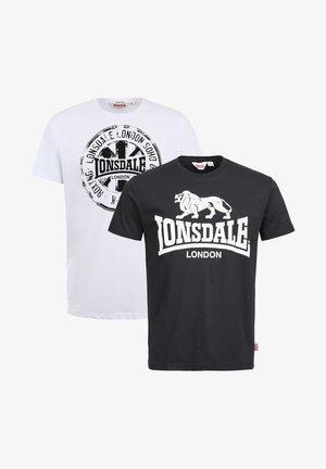 Dos camisetas: una blanca con un logo impreso circular y otra negra con un gráfico de león y "LONSDALE LONDON" en texto blanco. Material de algodón.