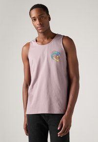 Svijetlopurple bez rukava majica od pamuka, s grafikom šarenih valova i životinja na prsima, u kombinaciji s tamnim hlačama.