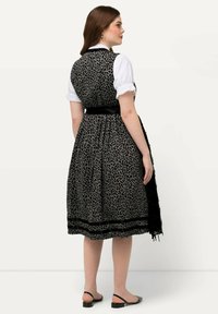 Vestido de leopardo en negro y gris con un corsé ajustado, falda amplia y cinturón de satén negro. Mangas abullonadas blancas, detalle decorativo en el dobladillo.