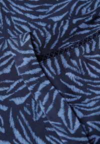 Tissu bleu marine avec un motif de feuilles bleues, d'une texture douce. Le design comprend un subtil détail en crochet le long du bord.