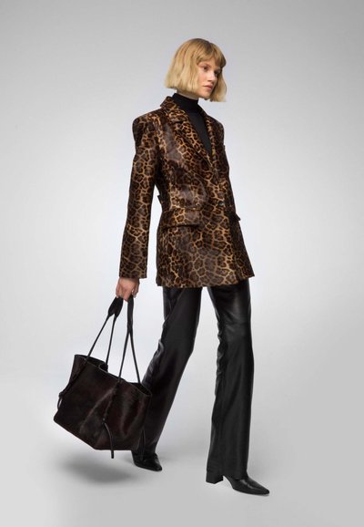 Leopard-print blazer with glossy texture, black turtleneck, black leather pants, and pointed-toe boots; carrying a textured black tote bag.