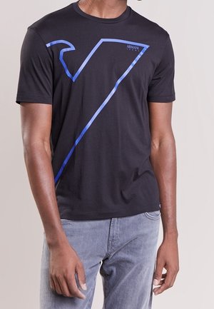 Czarny t-shirt z krótkim rękawem z dużym niebieskim konturem logo "7" oraz napisem "Armani Jeans", noszony przez osobę w jasnoniebieskich dżinsach.