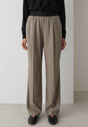 Plaid wide-leg trousers in beige and brown, featuring a high elastic waistband and soft, textured fabric. Tailored with front pleats.