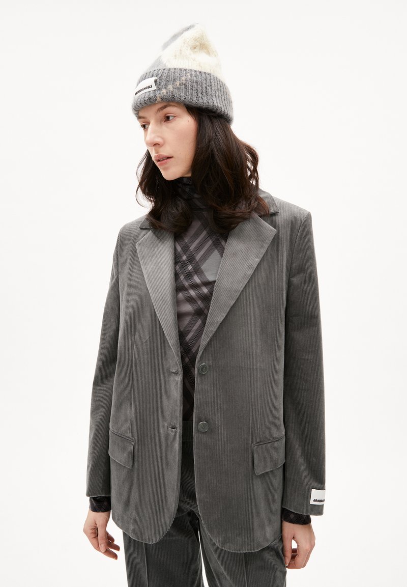 Grijze corduroy blazer met een reverskraag, twee knopen en opgestikte zakken, gelaagd over een gestreepte coltrui en gecombineerd met een gebreide beanie.