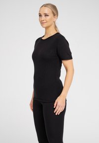 Black fitted T-shirt with short sleeves, round neckline, and ribbed texture. Paired with matching black leggings. Simple and streamlined design.