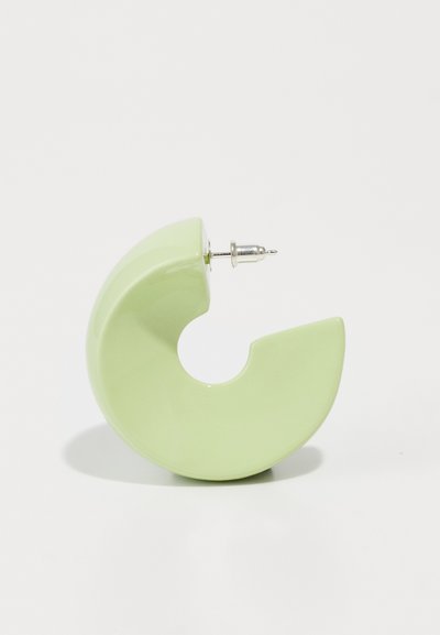 Cercei din ceramică verde, cu o formă abstractă curbată, având un finisaj polișat și un suport de ton argintiu. Remarcabili pentru textura lor lucioasă și designul unic.