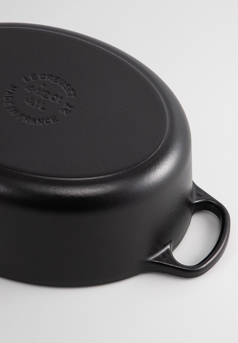 Schwarzer gusseiserner Le Creuset-Topf, kopfüber gezeigt, mit einem hervorgehobenen Griff und eingeprägten Marken- und Kapazitätsangaben an der Unterseite.
