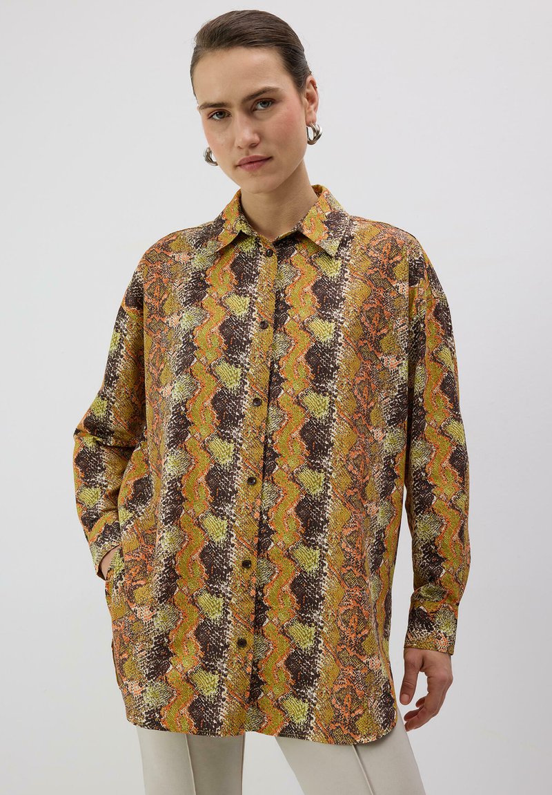 Chemise oversize imprimée avec un motif ondulé en marron, orange et vert. Fabriquée en tissu léger avec un col et un devant boutonné.