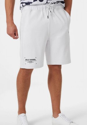 Shorts blancs en coton avec une taille élastique et un cordon de serrage, des poches latérales et un logo noir imprimé sur la jambe gauche.