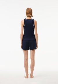 Top de baie navy cu margini albe, asociat cu pantaloni scurți asortați, realizat dintr-un material moale. Creat pentru confort, cu o croială lejeră.