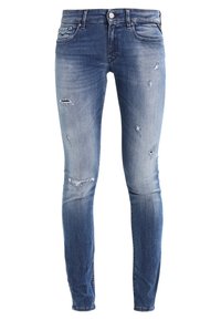 Jeans skinny de denim, con un degradado de azul claro a oscuro, parches desgastados y diseño estándar de cinco bolsillos con cierre de botón.