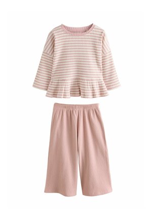 Langärmliges Oberteil mit rosa und weißem Karomuster und einem Peplum-Saum, kombiniert mit rosa gerippten weit geschnittenen Hosen. Aus weichem Baumwollmaterial.
