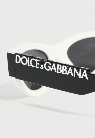 Κοντινή λήψη του μαύρου και λευκού βραχίονα γυαλιών ηλίου με ανάγλυλο λευκό λογότυπο Dolce & Gabbana σε μαύρο τμήμα της βάσης.
