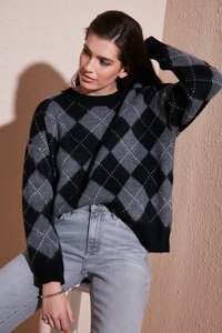 Maglione con motivo argyle in nero e grigio, con scollo rotondo, morbido al tatto e maniche lunghe, abbinato a jeans chiari a vita alta.