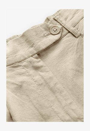 Beige linnedetalje med en knaplukning, glat tekstur og subtile sømlinjer, der fremhæver et rent og naturligt design.